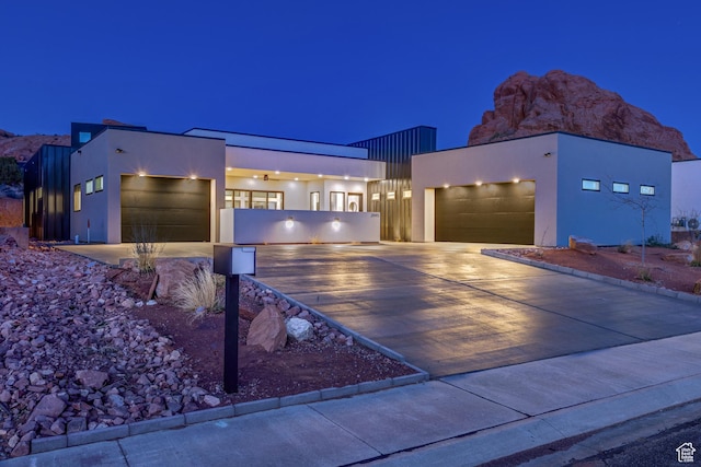 contemporary home featuring fence, a garage, driveway, and stucco siding