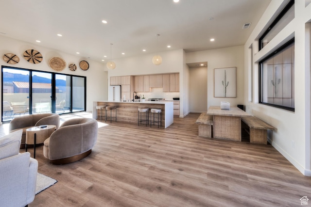 living room with recessed lighting, visible vents, baseboards, and light wood-style flooring