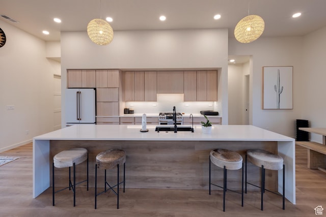 kitchen featuring a sink, visible vents, light wood-style flooring, and freestanding refrigerator