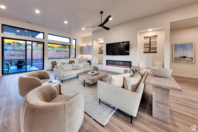 living room with visible vents, ceiling fan, light wood-type flooring, recessed lighting, and a glass covered fireplace