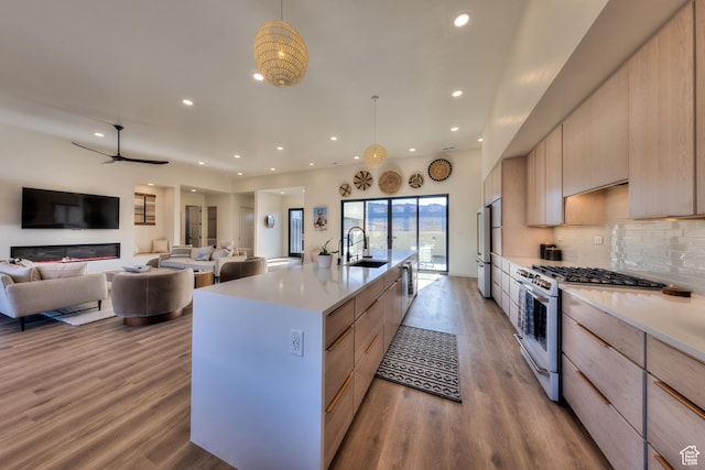kitchen featuring modern cabinets, light brown cabinets, a sink, wood finished floors, and white range with gas stovetop