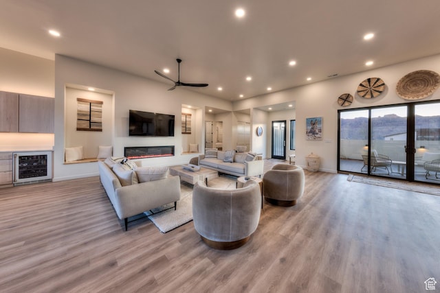 living room featuring a ceiling fan, recessed lighting, wine cooler, light wood-style floors, and baseboards