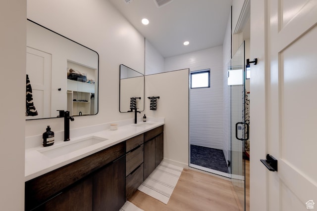 full bathroom with a stall shower, a sink, wood finished floors, recessed lighting, and double vanity
