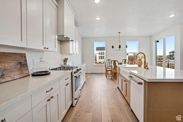 2878 W 2850 S, West Haven, UT 84401 - kitchen with high end stainless steel range oven, light wood-style floors, wall chimney exhaust hood, white dishwasher, and light countertops