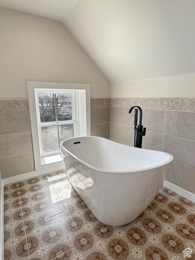 120 S 200 E, Castle Dale, UT 84513 - bathroom featuring tile patterned flooring, a wainscoted wall, vaulted ceiling, a freestanding tub, and tile walls
