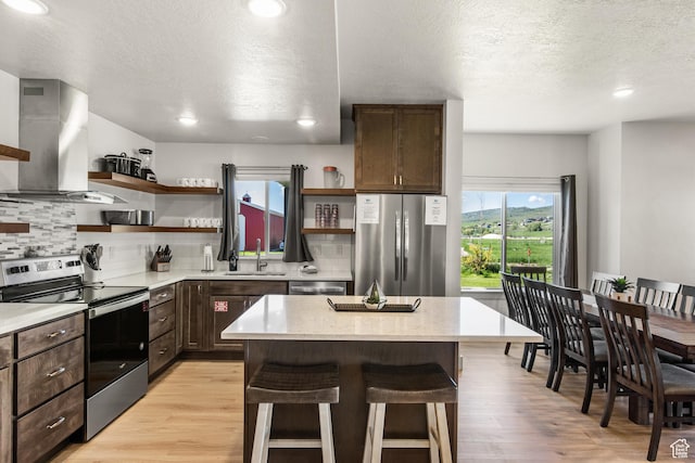 140 W 150th St S Unit D12, Garden City, UT 84028 - kitchen with dark brown cabinetry, appliances with stainless steel finishes, a kitchen breakfast bar, wall chimney exhaust hood, and open shelves