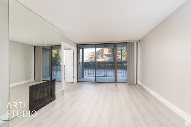 unfurnished living room with wood finished floors, baseboards, and expansive windows