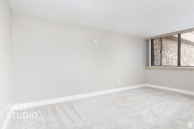 spare room featuring carpet and baseboards