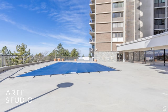 community pool with a patio and fence