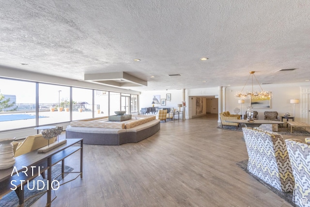 living area with visible vents, a textured ceiling, an inviting chandelier, and wood finished floors