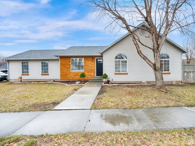 ranch-style house featuring a front lawn and fence