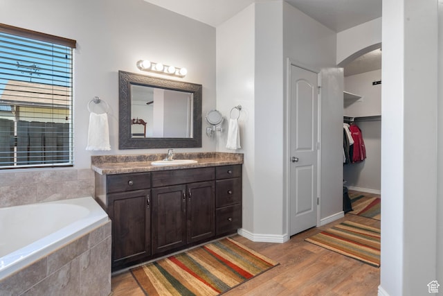 265 E Kimball Ct, Washington, UT 84780 - full bathroom featuring vanity, wood finished floors, baseboards, a walk in closet, and a garden tub