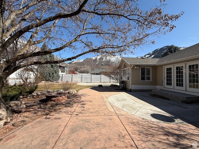 view of patio with a mountain view, entry steps, and fence