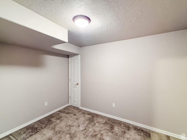 spare room featuring baseboards, carpet floors, and a textured ceiling