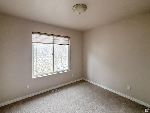 empty room featuring visible vents, baseboards, and carpet