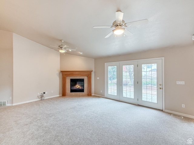 unfurnished living room featuring visible vents, carpet floors, lofted ceiling, ceiling fan, and a tiled fireplace