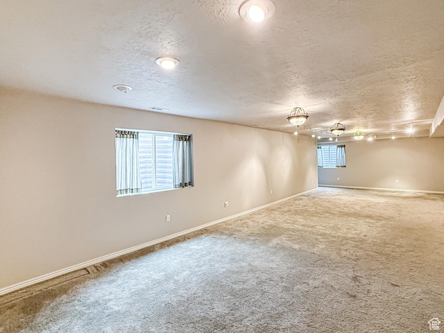 unfurnished room featuring visible vents, carpet floors, a textured ceiling, and baseboards