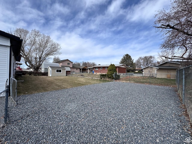 view of yard featuring a residential view, an outdoor structure, and fence