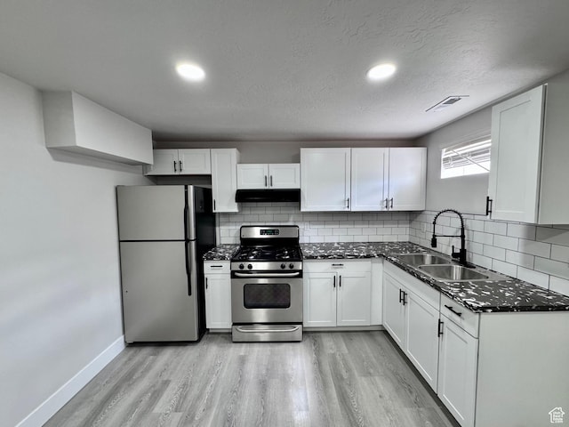 kitchen featuring a sink, light wood-type flooring, under cabinet range hood, stainless steel appliances, and visible vents