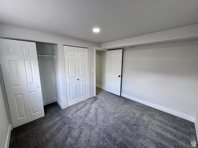 unfurnished bedroom with baseboards, dark colored carpet, and a textured ceiling