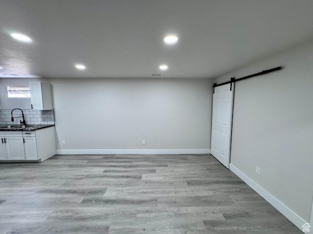 interior space featuring baseboards, a barn door, a sink, and light wood finished floors