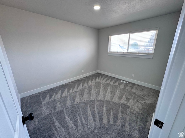 carpeted empty room with baseboards, a textured ceiling, and visible vents