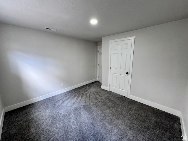 unfurnished bedroom featuring dark carpet, baseboards, and visible vents