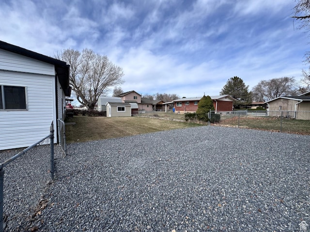 view of yard featuring an outbuilding, fence, and a residential view