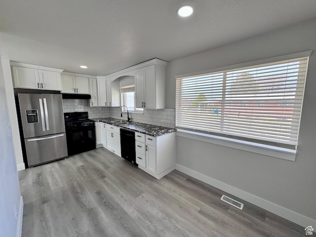 kitchen featuring visible vents, tasteful backsplash, under cabinet range hood, a sink, and black appliances
