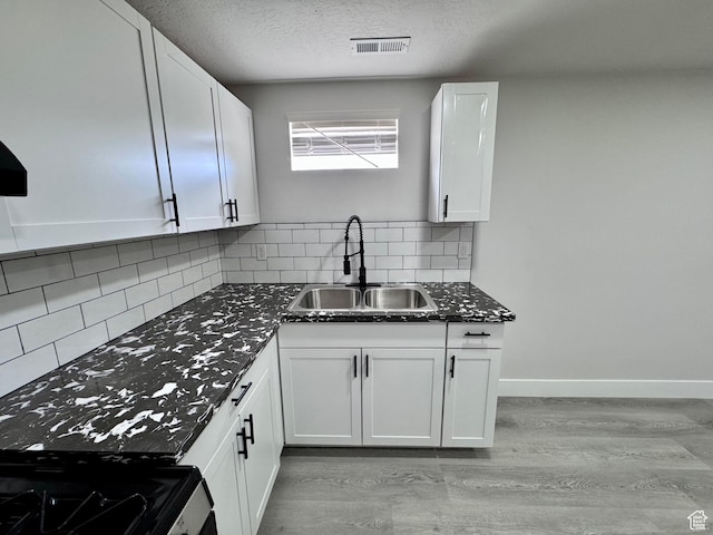 kitchen with a sink, stainless steel range with gas cooktop, light wood finished floors, and visible vents