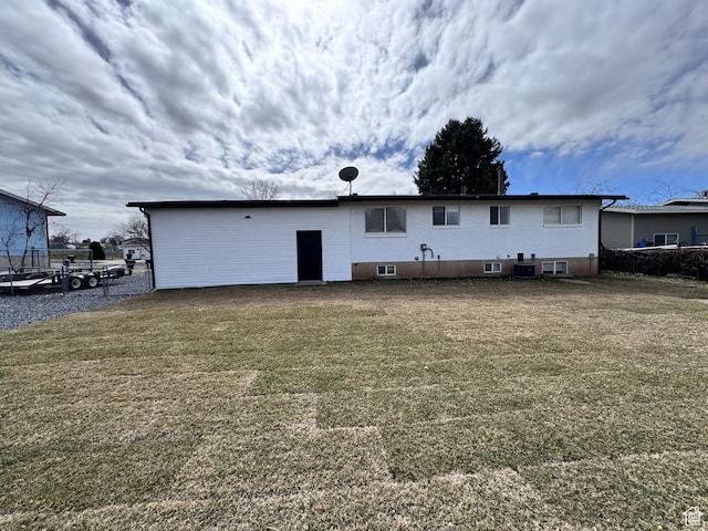 rear view of house with central AC and a lawn