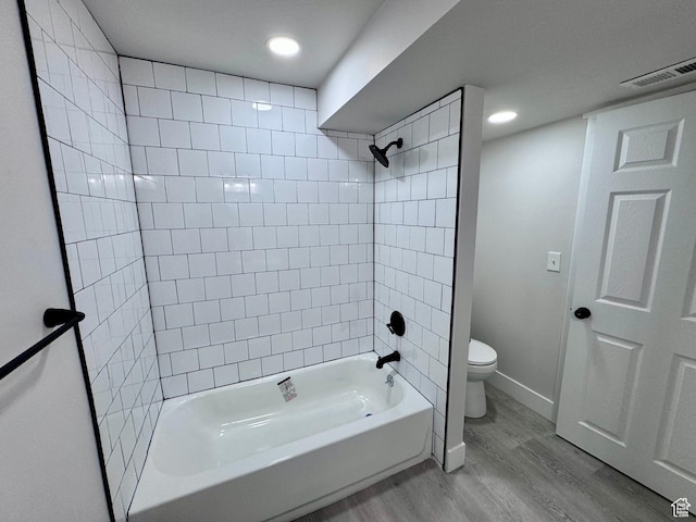 bathroom featuring toilet, baseboards, bathtub / shower combination, visible vents, and wood finished floors