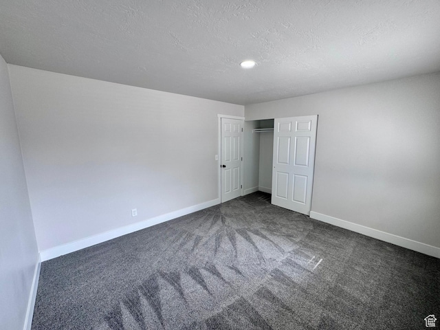 unfurnished bedroom featuring baseboards, a closet, carpet floors, and a textured ceiling