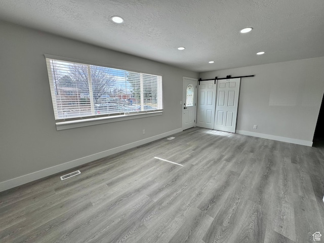 unfurnished bedroom with baseboards, a barn door, and visible vents