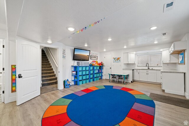 playroom with recessed lighting, visible vents, light wood-type flooring, and a sink