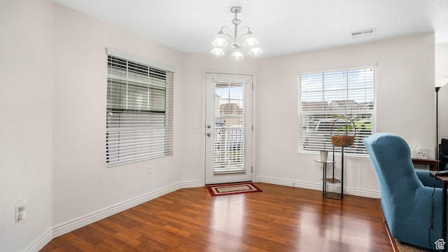 unfurnished office featuring a chandelier, visible vents, baseboards, and wood finished floors