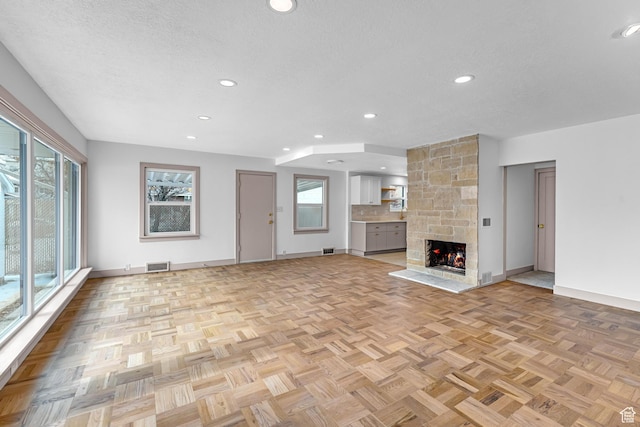 130 E 200 S, Provo, UT 84606 - unfurnished living room featuring visible vents, baseboards, a stone fireplace, recessed lighting, and a textured ceiling