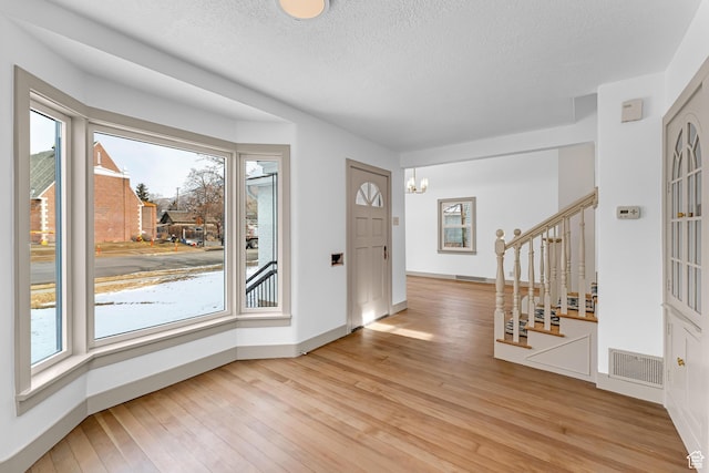 130 E 200 S, Provo, UT 84606 - foyer entrance with light wood finished floors, visible vents, a chandelier, stairway, and a textured ceiling