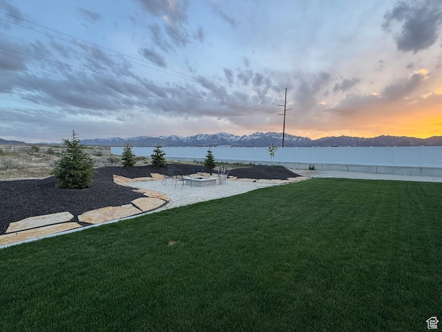 134 E Marciano Way, Grantsville, UT 84029 - yard at dusk featuring a patio area, a fire pit, a mountain view, and a fenced backyard
