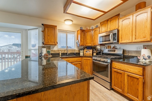 2602 W 1800 S, West Haven, UT 84401 - kitchen with light wood-style flooring, a peninsula, dark stone countertops, a sink, and stainless steel appliances