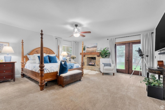 bedroom featuring a stone fireplace, a ceiling fan, carpet, and access to outside