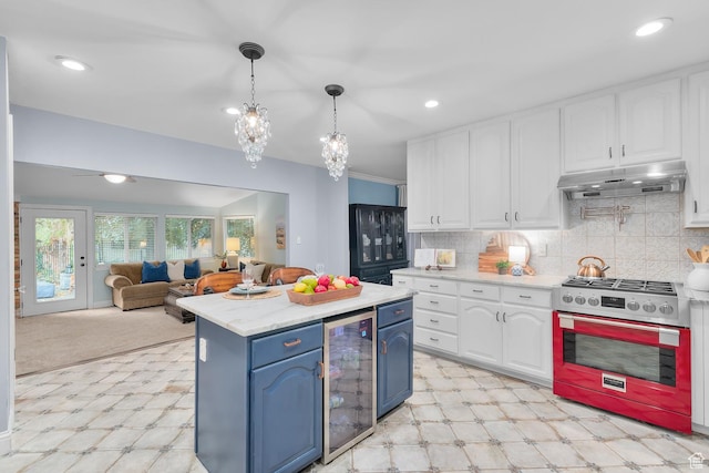 kitchen featuring blue cabinetry, under cabinet range hood, beverage cooler, light floors, and gas stove