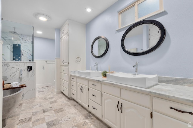 bathroom with a marble finish shower, wainscoting, double vanity, and a sink