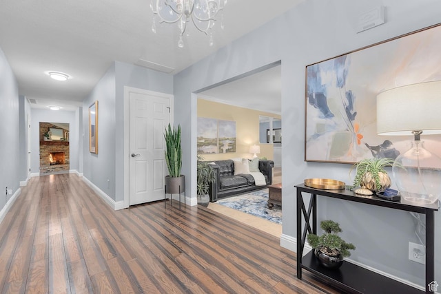 hallway featuring wood finished floors, baseboards, and a chandelier
