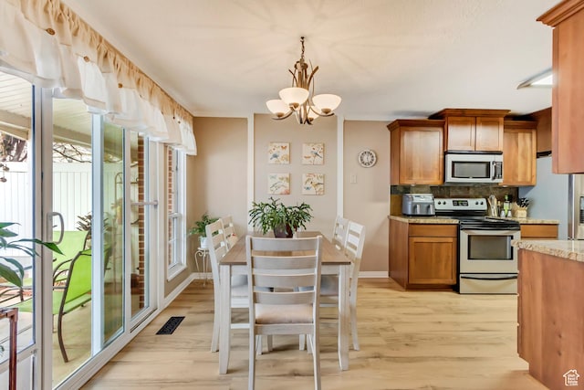 203 W Pheasantbrook Dr N, Centerville, UT 84014 - kitchen featuring an inviting chandelier, light wood-style flooring, stainless steel appliances, brown cabinets, and backsplash