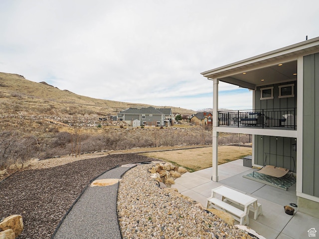 view of yard featuring a balcony, a mountain view, and a patio