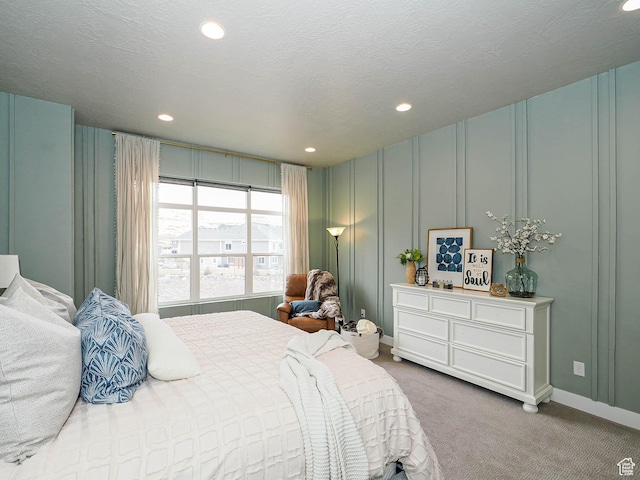 carpeted bedroom featuring a decorative wall, recessed lighting, baseboards, and a textured ceiling