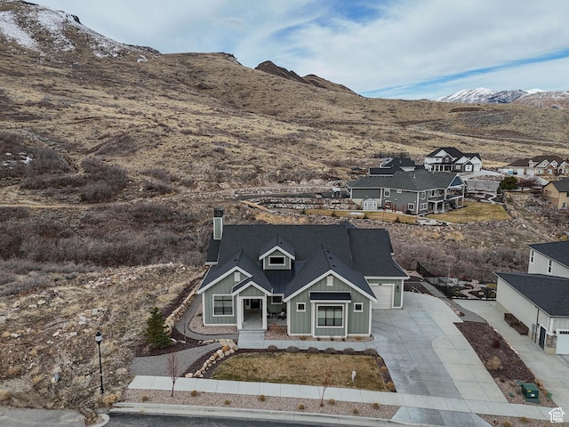 exterior space featuring a mountain view, a chimney, board and batten siding, and driveway