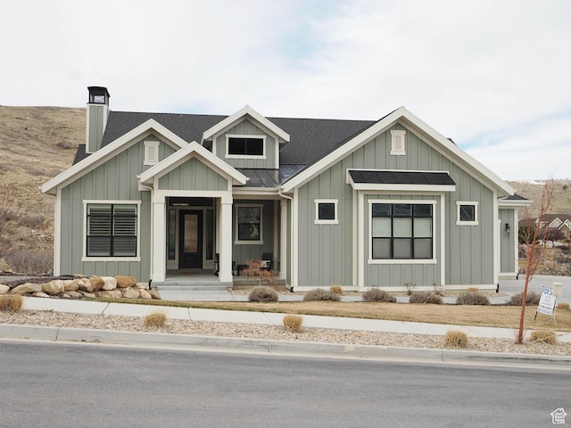 view of front of property featuring board and batten siding, a chimney, a standing seam roof, and metal roof