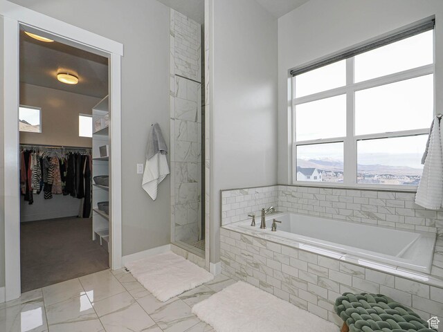full bath featuring baseboards, a stall shower, a walk in closet, a garden tub, and marble finish floor